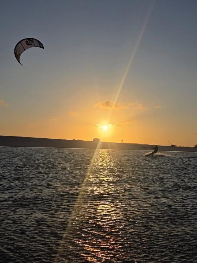 Silhueta de kitesurfista saltando ao entardecer
