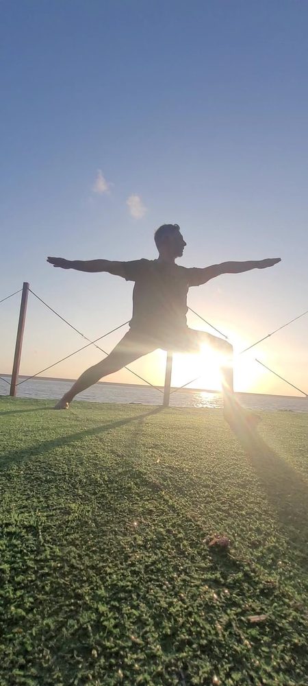 Postura de guerreiro em ioga ao pôr do sol