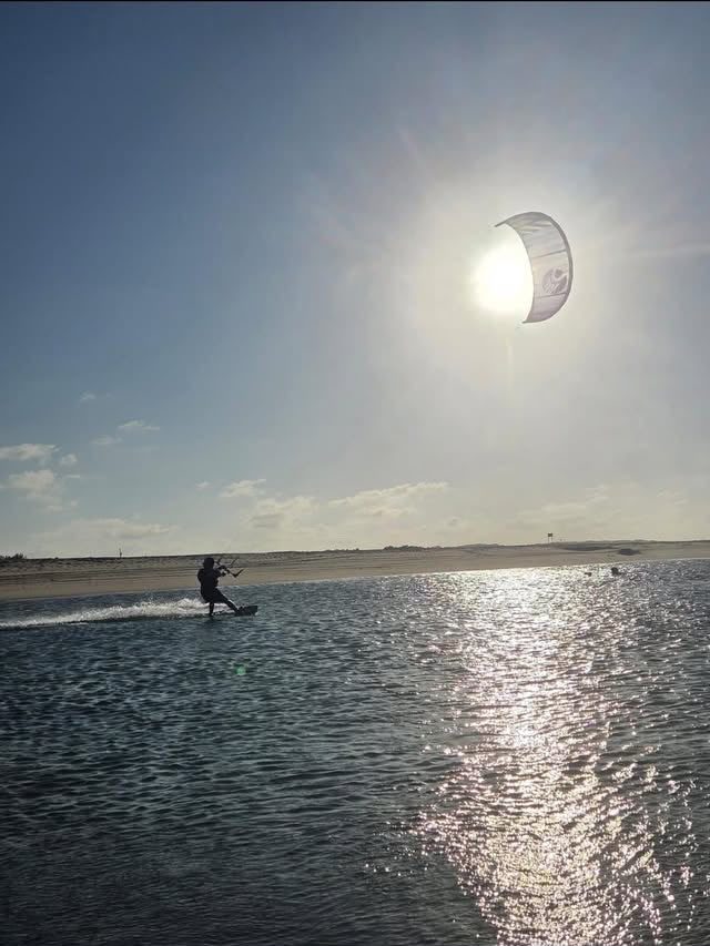 Kitesurfista distante com kite em forma de lua sobre a lagoa