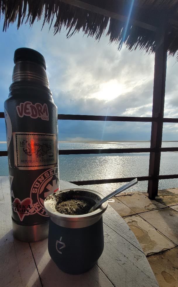 Cuia de mate numa varanda de madeira com vista para a lagoa